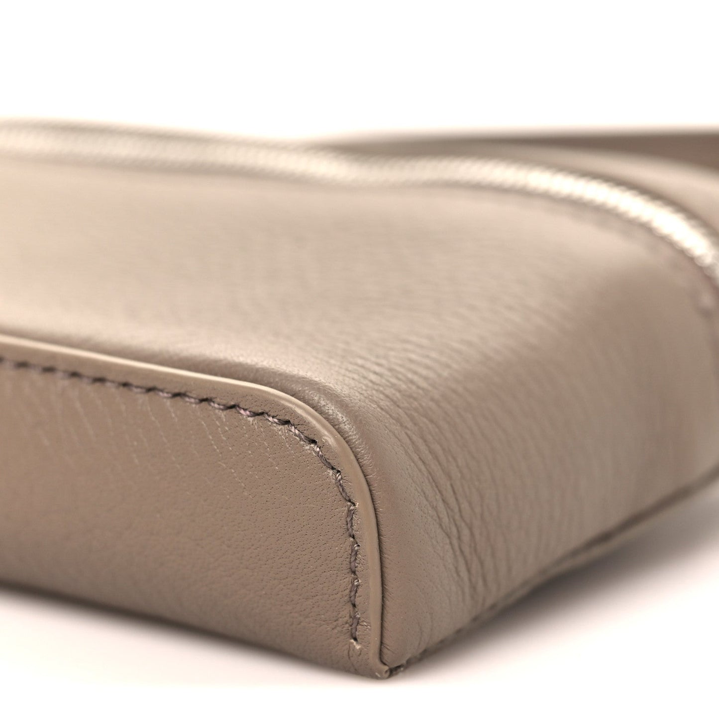 Bottom edge of a grained leather mini pouch with rounded corner seam