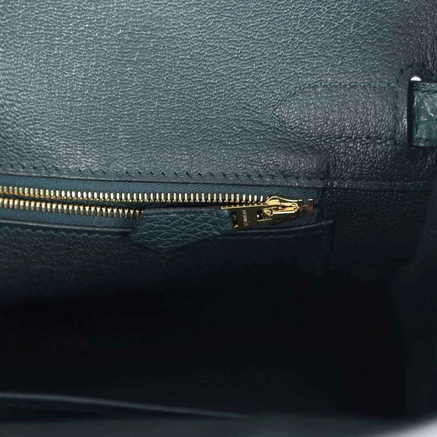 Elegant black leather handbag interior with gold zipper, showcasing refined, timeless style.