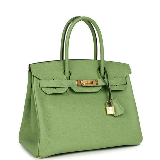 Elegant light green leather handbag with gold hardware and double top handles, sophisticated design