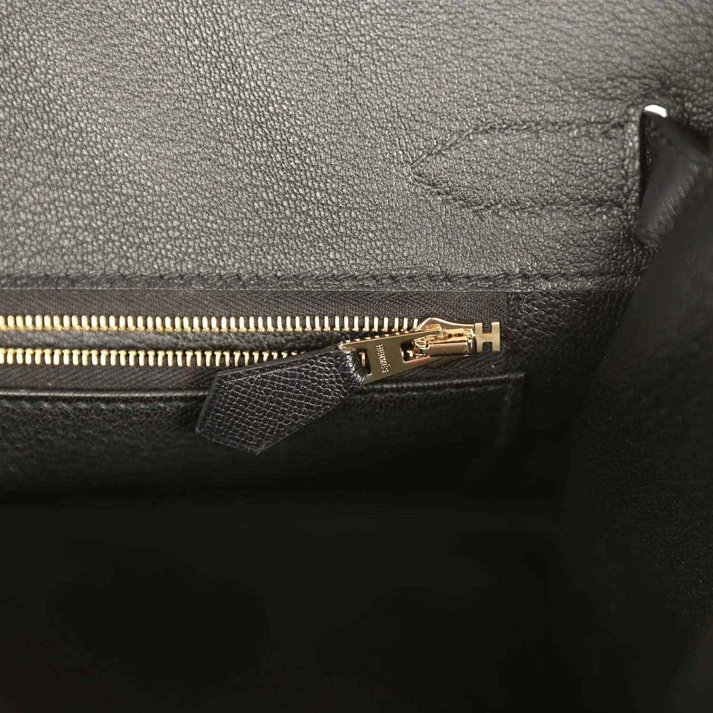 Elegant black leather handbag interior with gold zipper and refined stitching, timeless style