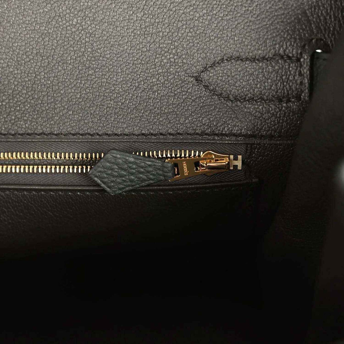 Elegant black leather handbag interior with gold zipper and refined stitching detail