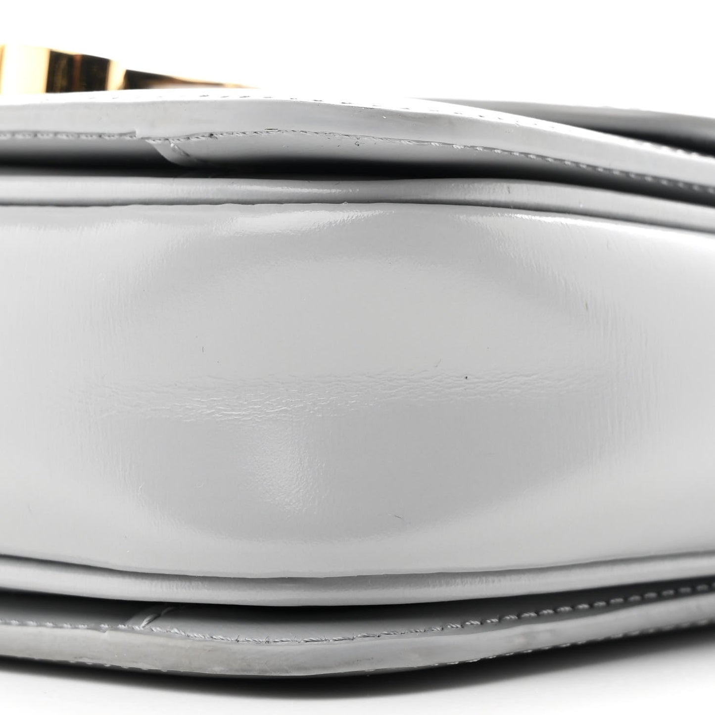 Shiny calfskin bag bottom edge with stitching and layered construction close-up