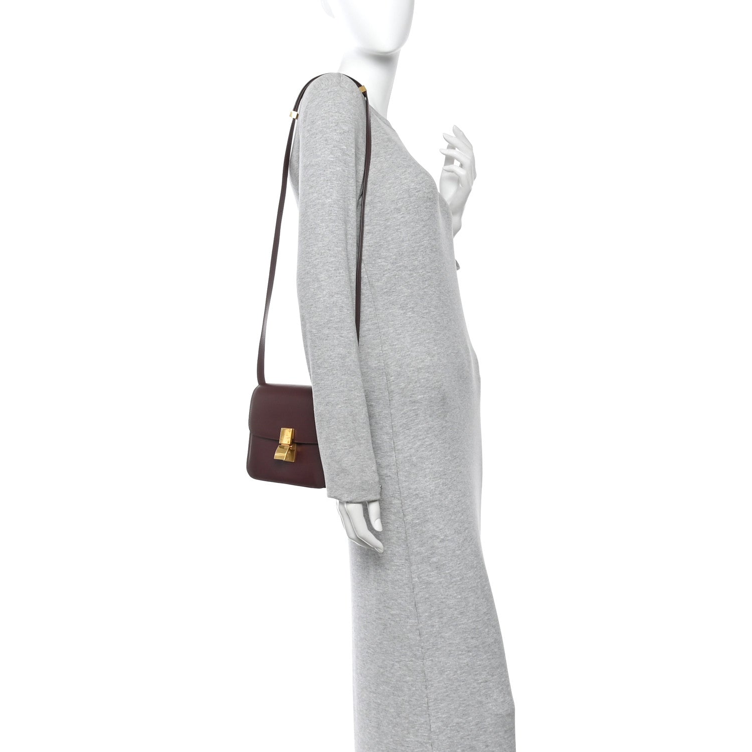 Burgundy leather shoulder flap bag on a mannequin, gold-tone clasp and short handle.