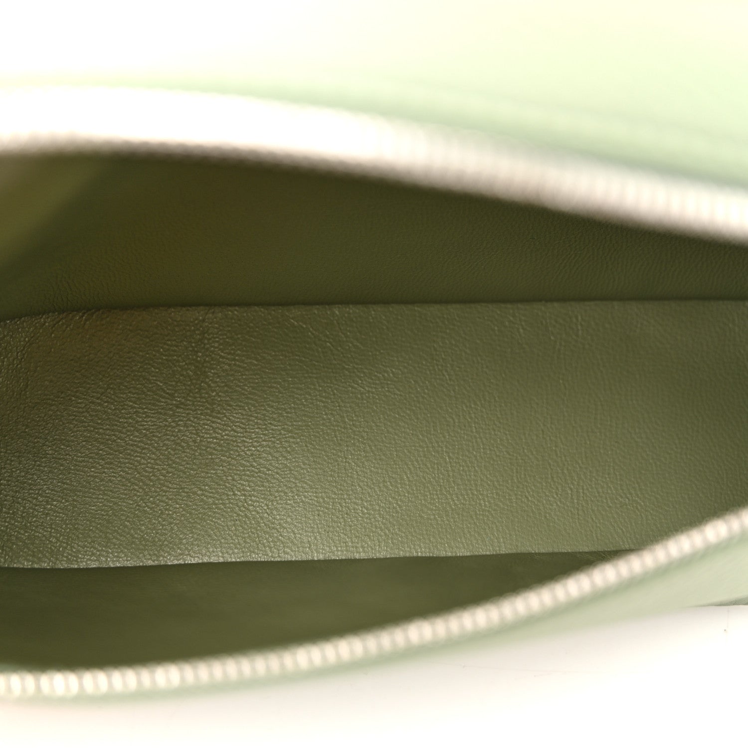 Sage green leather pouch interior with top zipper edge visible