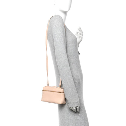Cream leather mini pouch crossbody with strap and gold zip, worn on mannequin