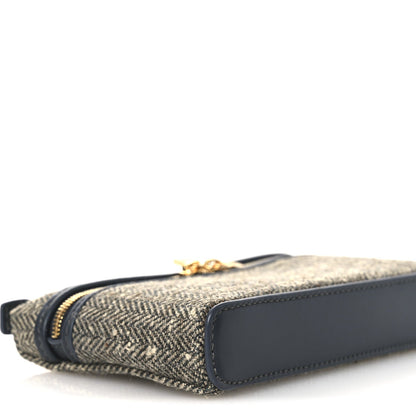 Mini pouch corner with herringbone body, navy leather trim, and gold zipper edge