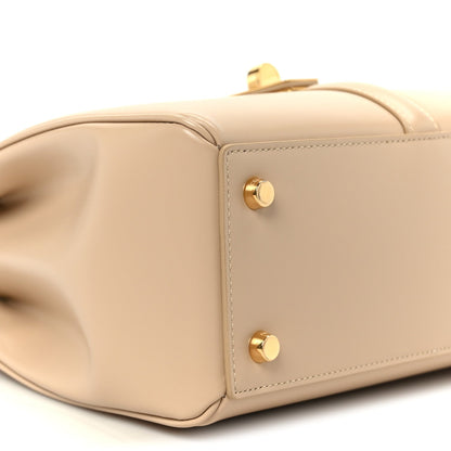 Nude small top-handle bag side with two gold snap buttons