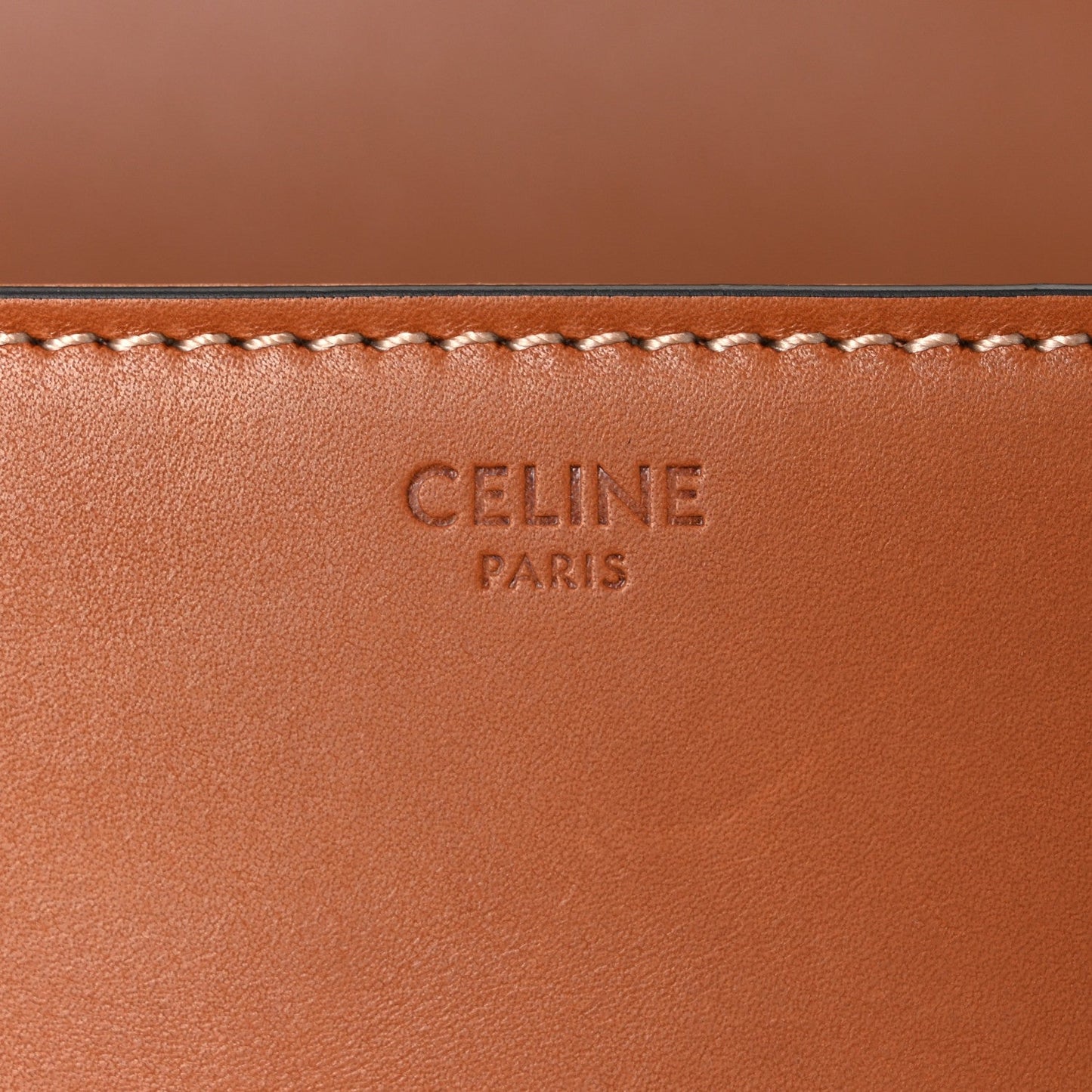 Celine embossed mark on tan leather panel with decorative stitched trim.
