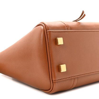 Tan leather tote front corner with gold-tone stud hardware and seam stitching