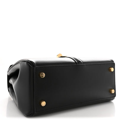 Black structured tote-style bag with top handle and gold snaps on front panel