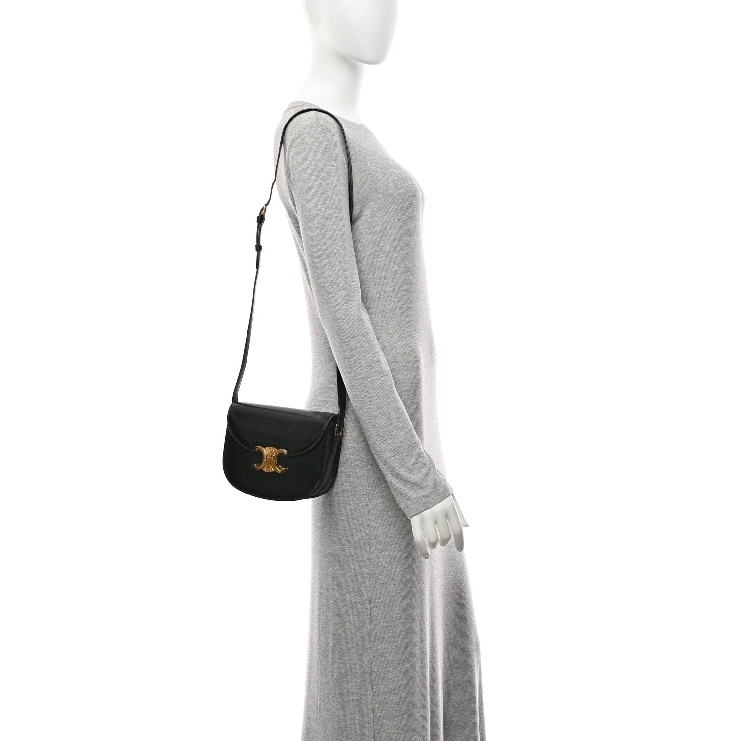 Black leather crossbody bag with gold emblem on the flap, worn with a slim shoulder strap