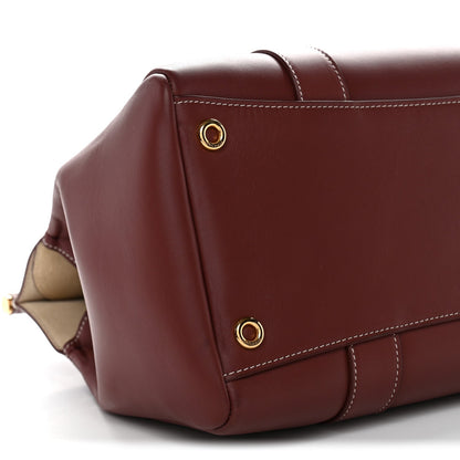 Calfskin bag corner with gold snap studs and stitched flap edge, dark brown