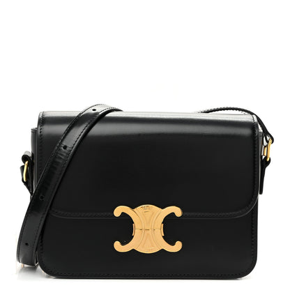 Black shiny calfskin shoulder bag with gold logo and top flap, adjustable strap.