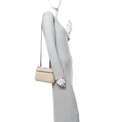 Cream faux-fur crossbody pouch with brown leather strap worn at side