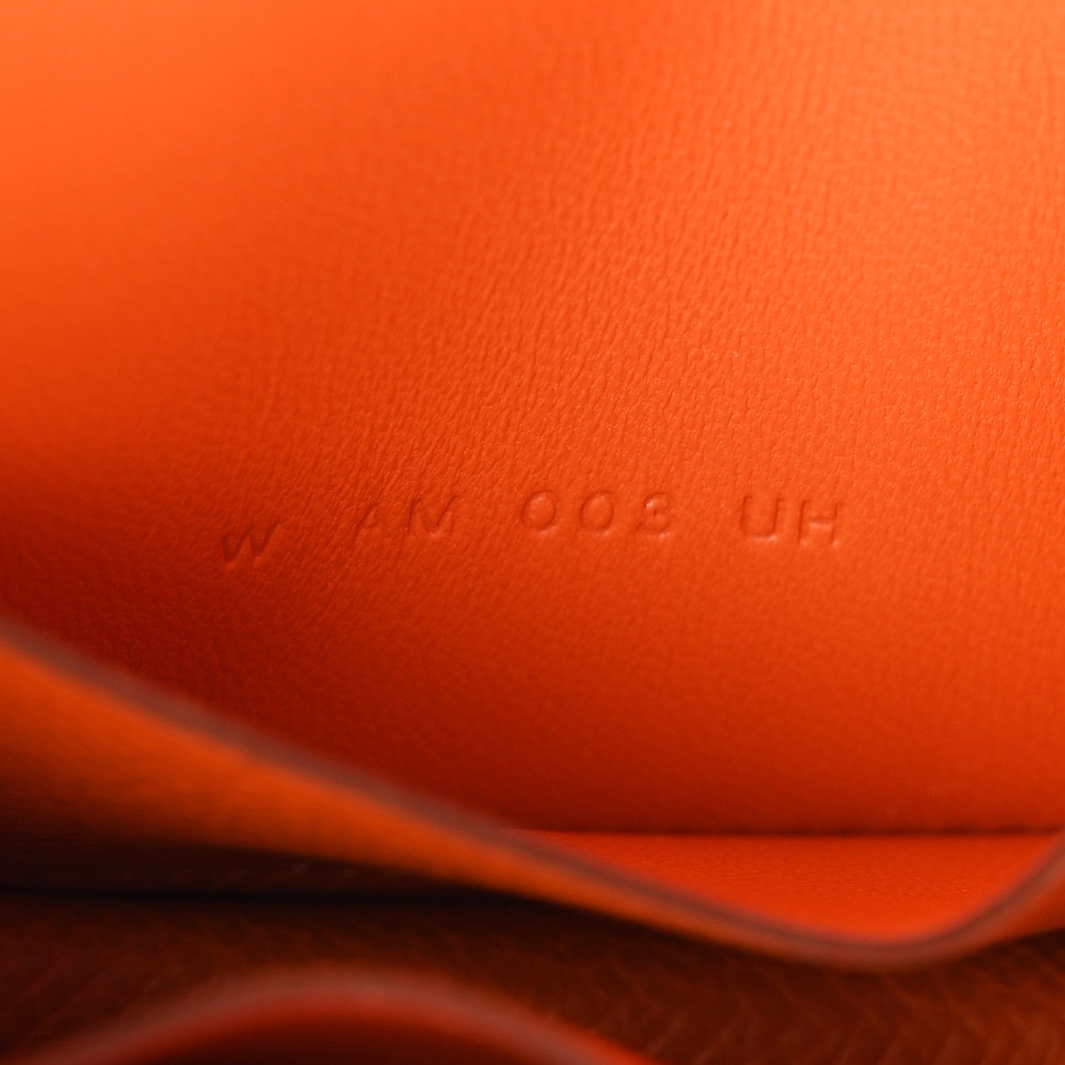 Embossed markings on orange Epsom leather slim wallet interior.