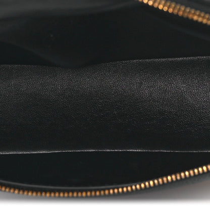 Black grained leather close-up with gold-tone zipper teeth along the opening