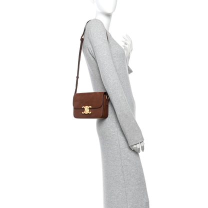 Chestnut leather shoulder bag worn crossbody by a model with gold logo