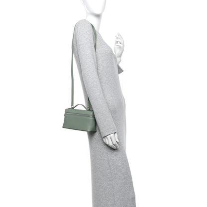 Sage green leather mini pouch with crossbody strap, worn at side