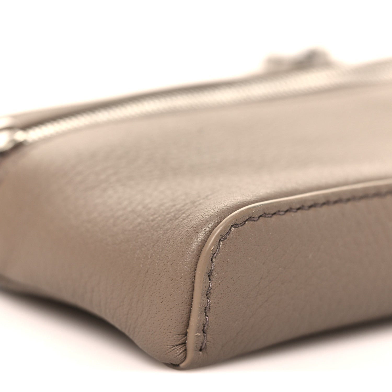 Corner detail of a mini grained leather pouch with visible edge stitching