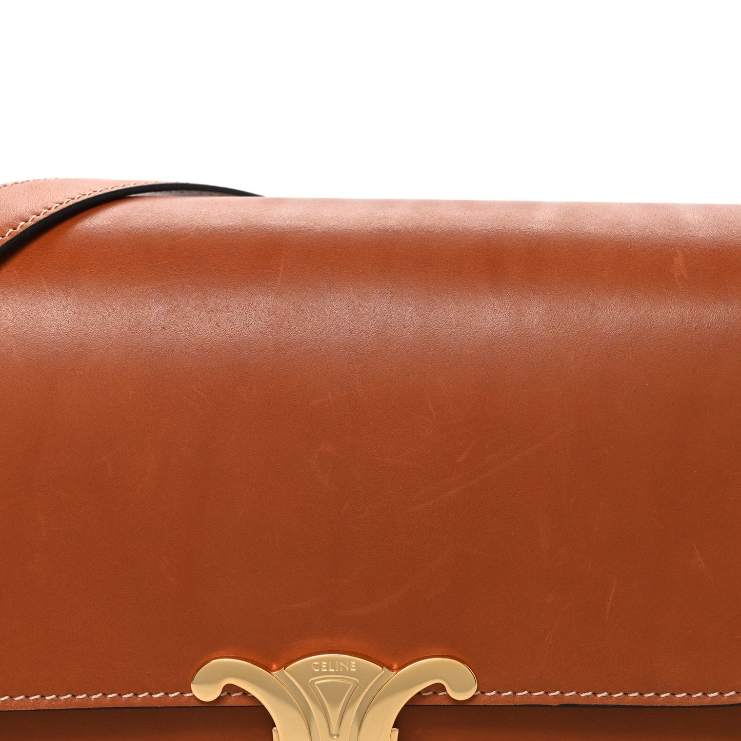 Tan shoulder bag flap with gold-tone Celine emblem and braided edge stitching.