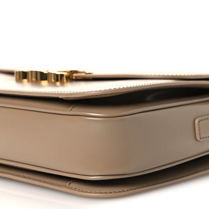 Shiny brown leather shoulder bag with gold-tone clasp hardware and top seam