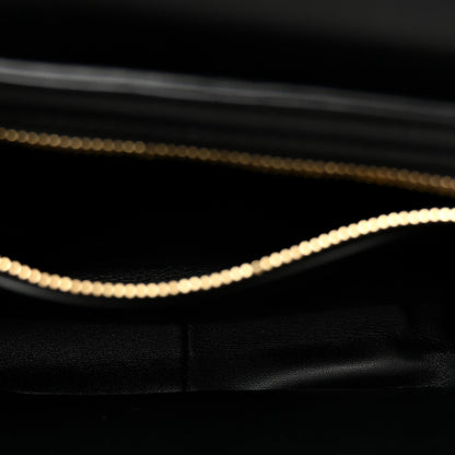 Close-up of black leather bag interior edge with gold chain trim.