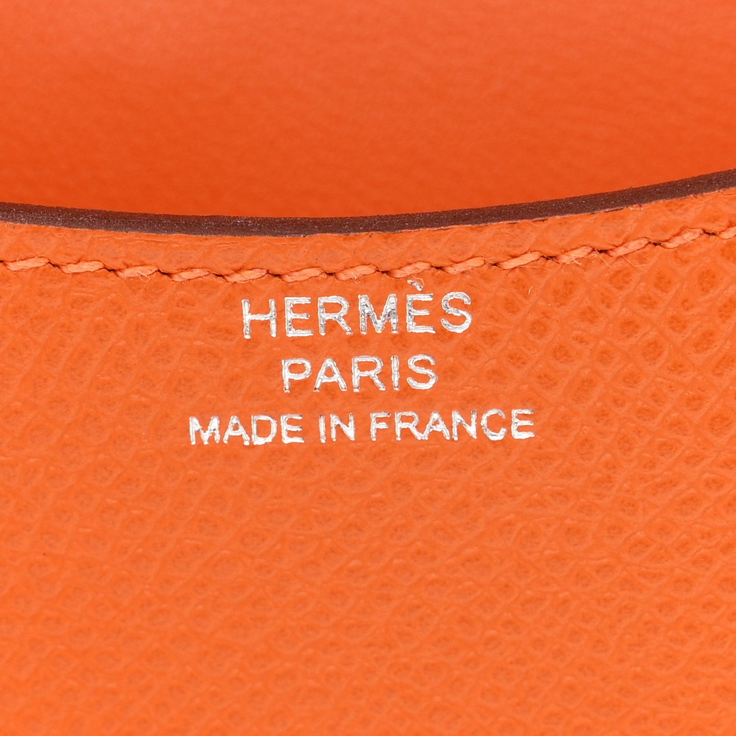 Hermes Paris Made in France stamp on orange leather slim wallet.