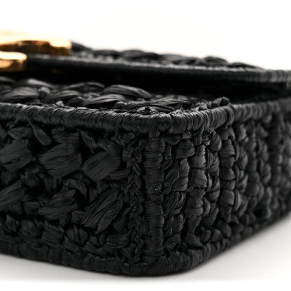 Black woven raffia-effect bag side with out-of-focus chain hardware
