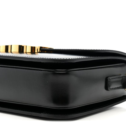 Black leather crossbody bag close-up with gold clasp, top edge, and strap tab.