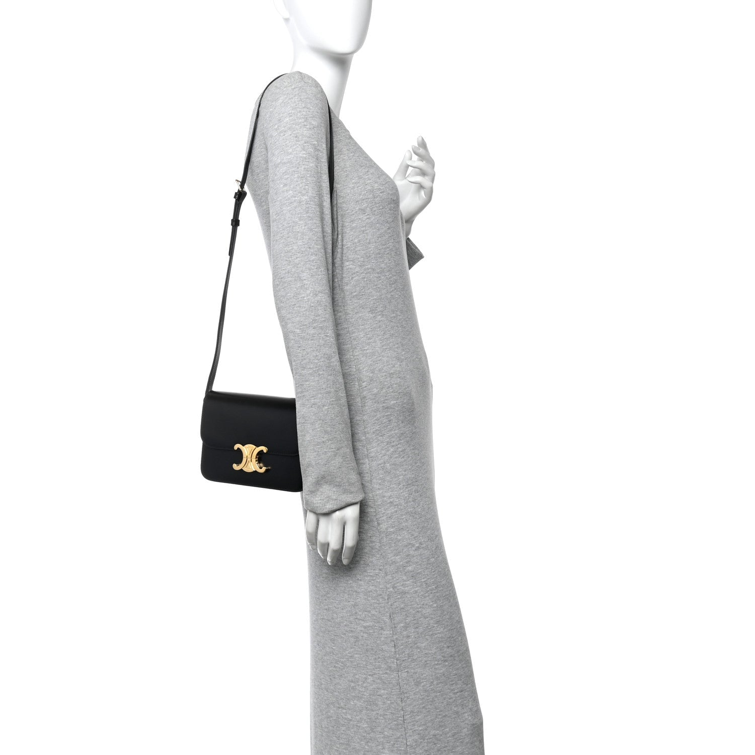 Small black leather crossbody bag on model with gold logo hardware and flap closure.