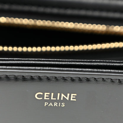 Close-up of black leather bag stitching and gold chain detail.