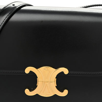Close-up of black shiny flap with gold C logo ornament and top stitching.