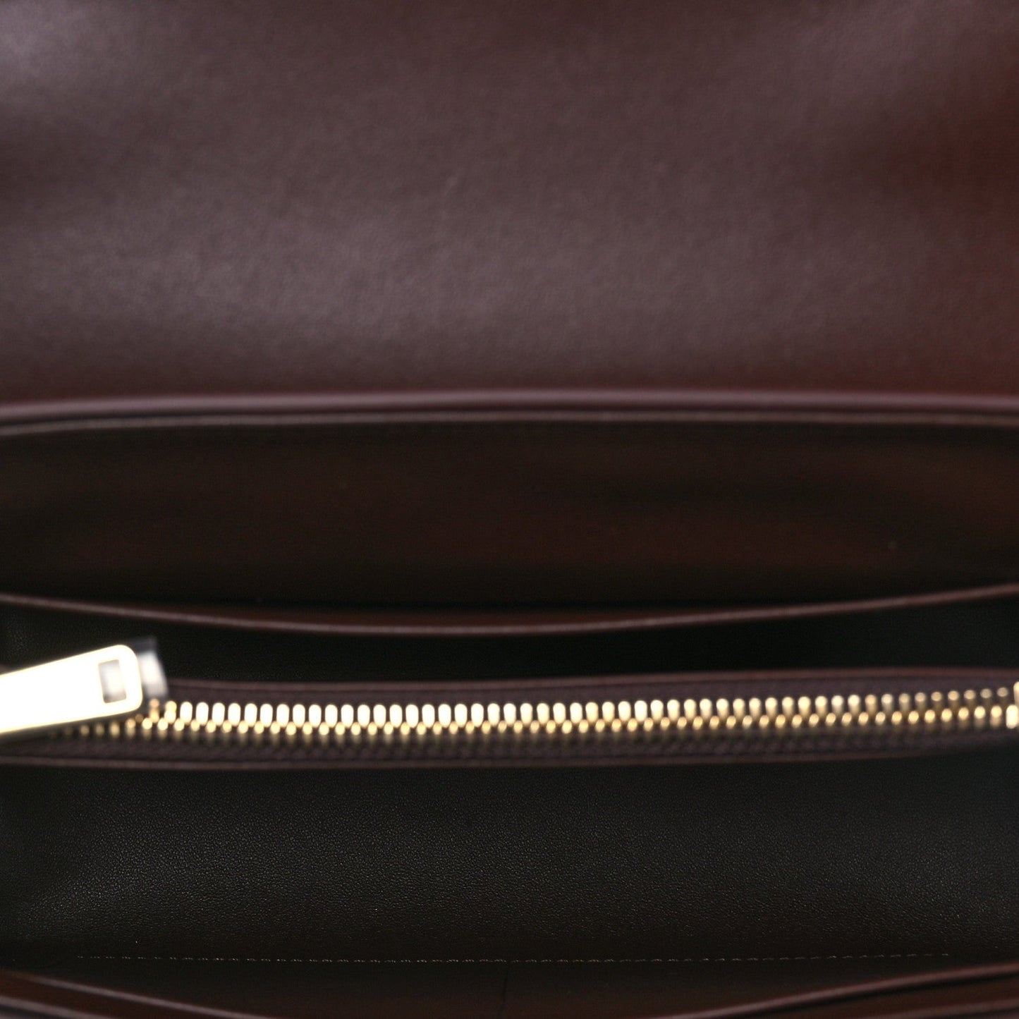 Leather bag interior view with gold zipper and dark lining pocket.