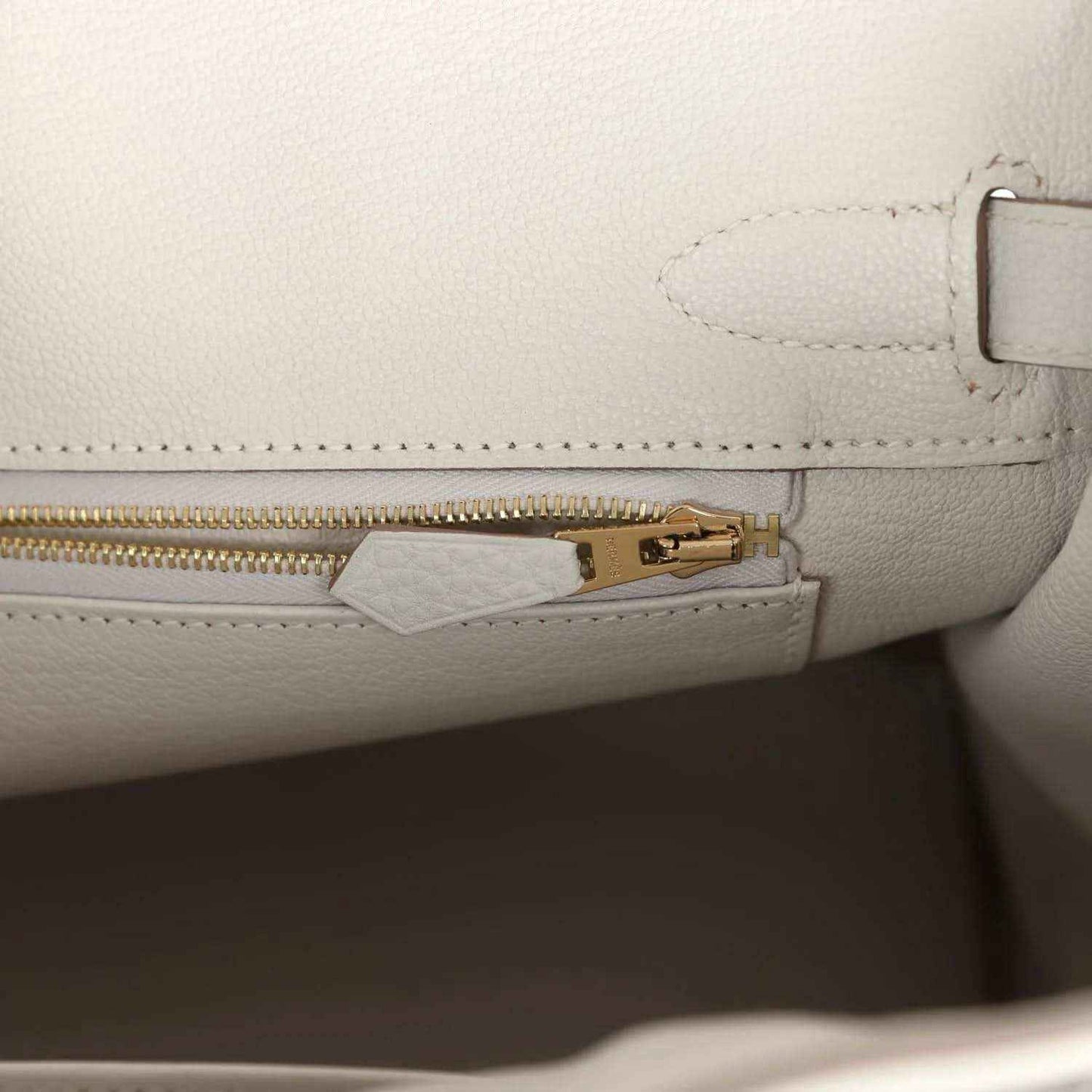 Elegant white leather handbag interior with gold zipper, sophisticated and timeless.