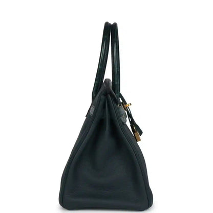 Side view of an elegant dark green leather handbag with gold hardware and a timeless silhouette.