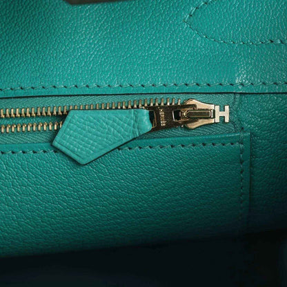 Elegant teal leather handbag close-up with gold zipper, showcasing timeless sophistication.