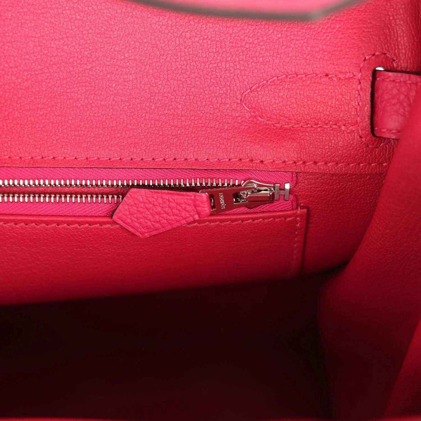 Elegant pink leather handbag interior with silver zipper, showcasing timeless craftsmanship