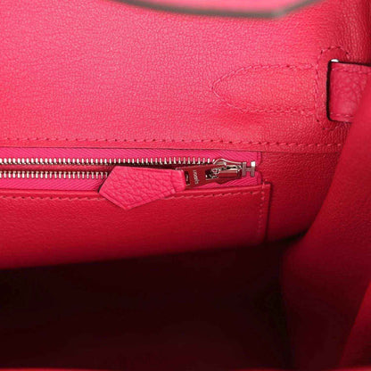Elegant pink leather handbag interior with silver zipper, showcasing timeless craftsmanship