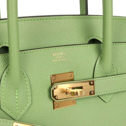Elegant light green leather handbag with gold hardware and refined stitching, timeless and sophisticated.