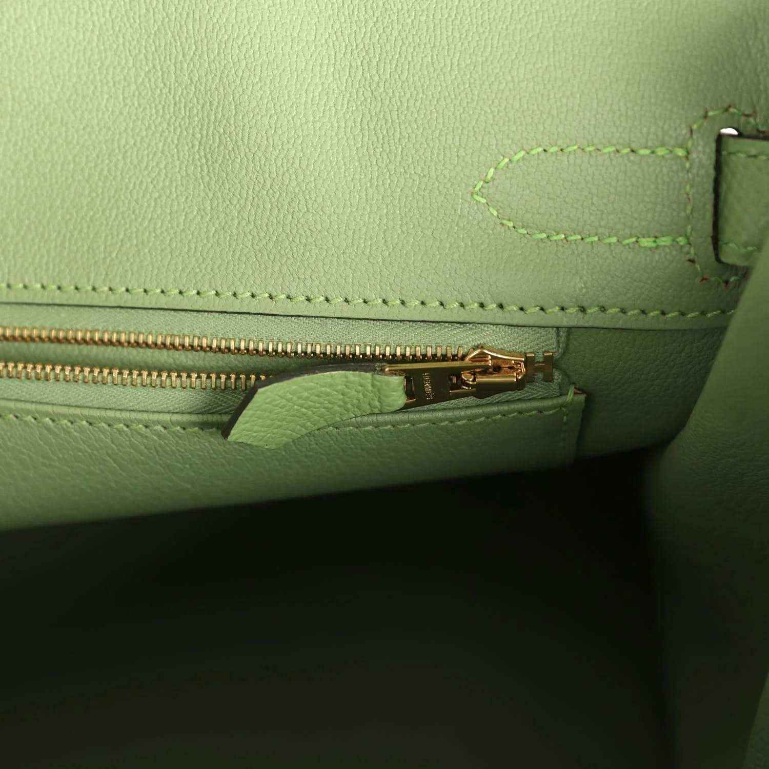 Elegant mint green leather handbag interior with gold zipper, showcasing timeless sophistication.