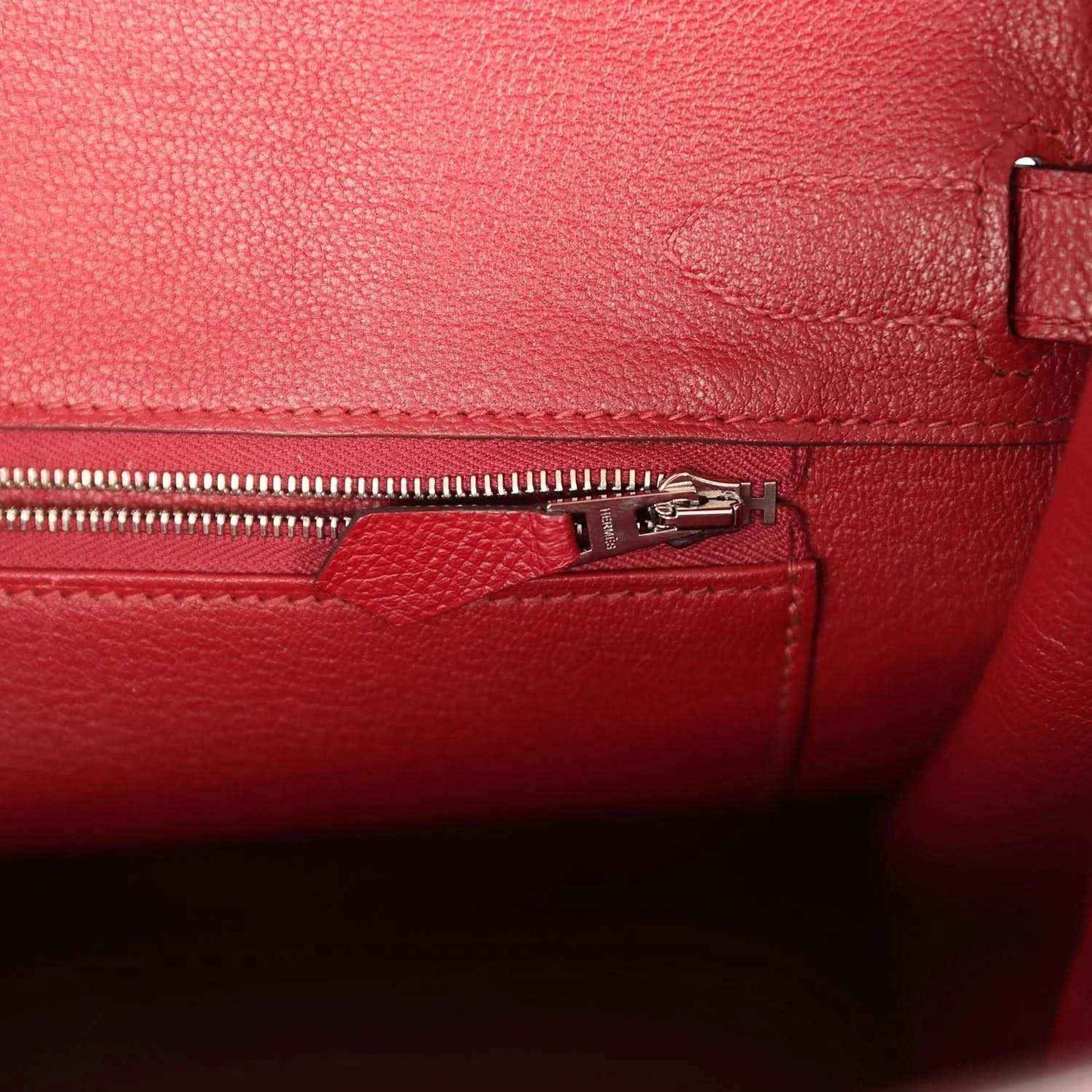 Elegant red leather handbag interior with refined zipper pocket and textured finish