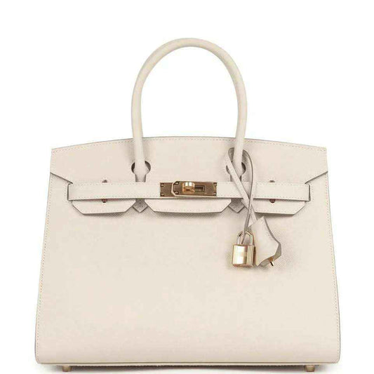 Timeless ivory leather handbag with gold hardware and elegant structured design.