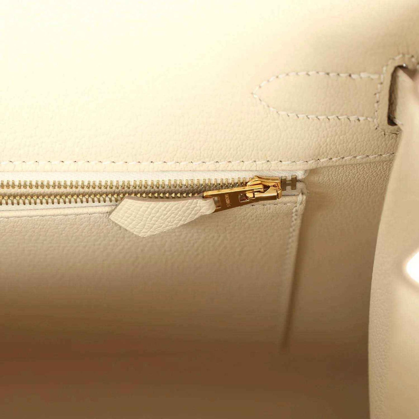 Elegant cream leather handbag interior with gold zipper and refined stitching