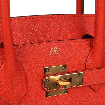 Timeless red leather handbag with gold hardware and elegant textured finish.