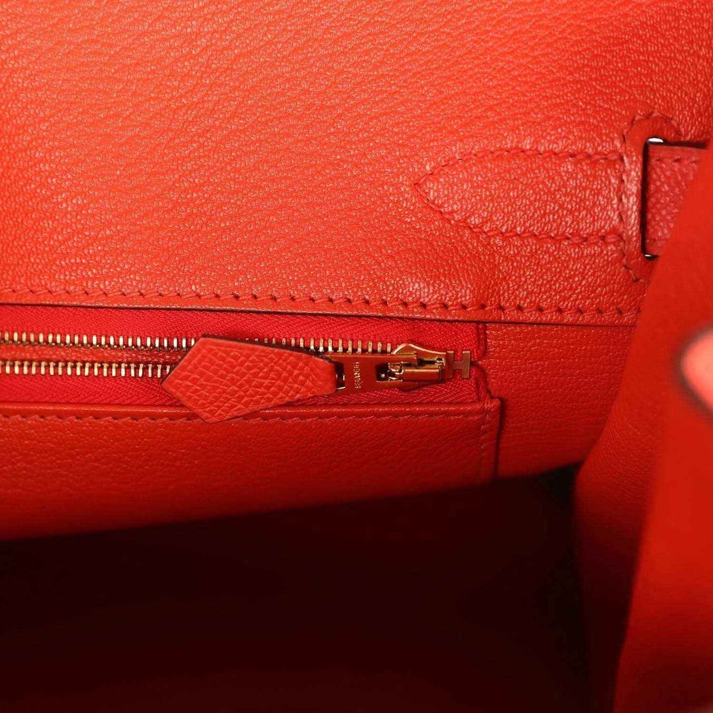 Elegant red leather handbag interior with gold zipper and refined stitching