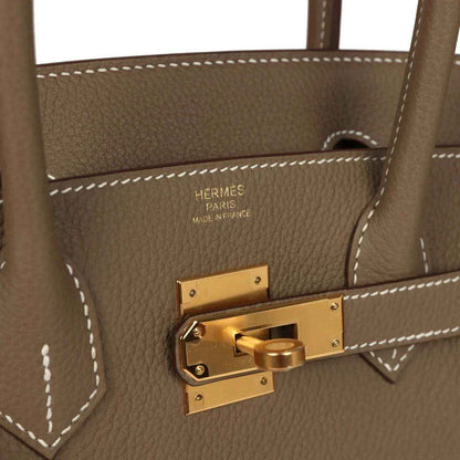 Timeless taupe leather handbag with elegant gold hardware and sophisticated stitching detail
