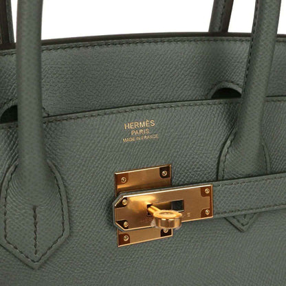 Elegant dark grey leather handbag with gold hardware and sophisticated detailing.
