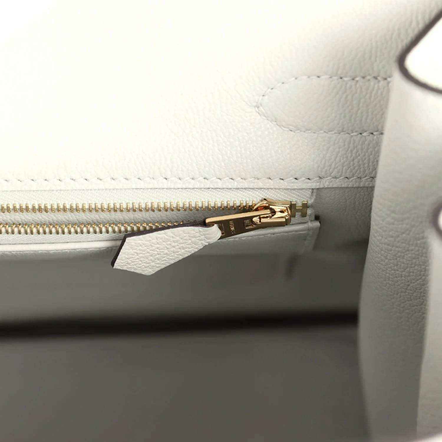 Elegant white leather handbag interior with gold zipper, showcasing timeless sophistication.