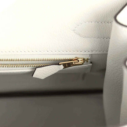 Elegant white leather handbag interior with gold zipper, showcasing timeless sophistication.