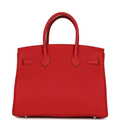Elegant red leather handbag with structured silhouette and timeless, sophisticated design.